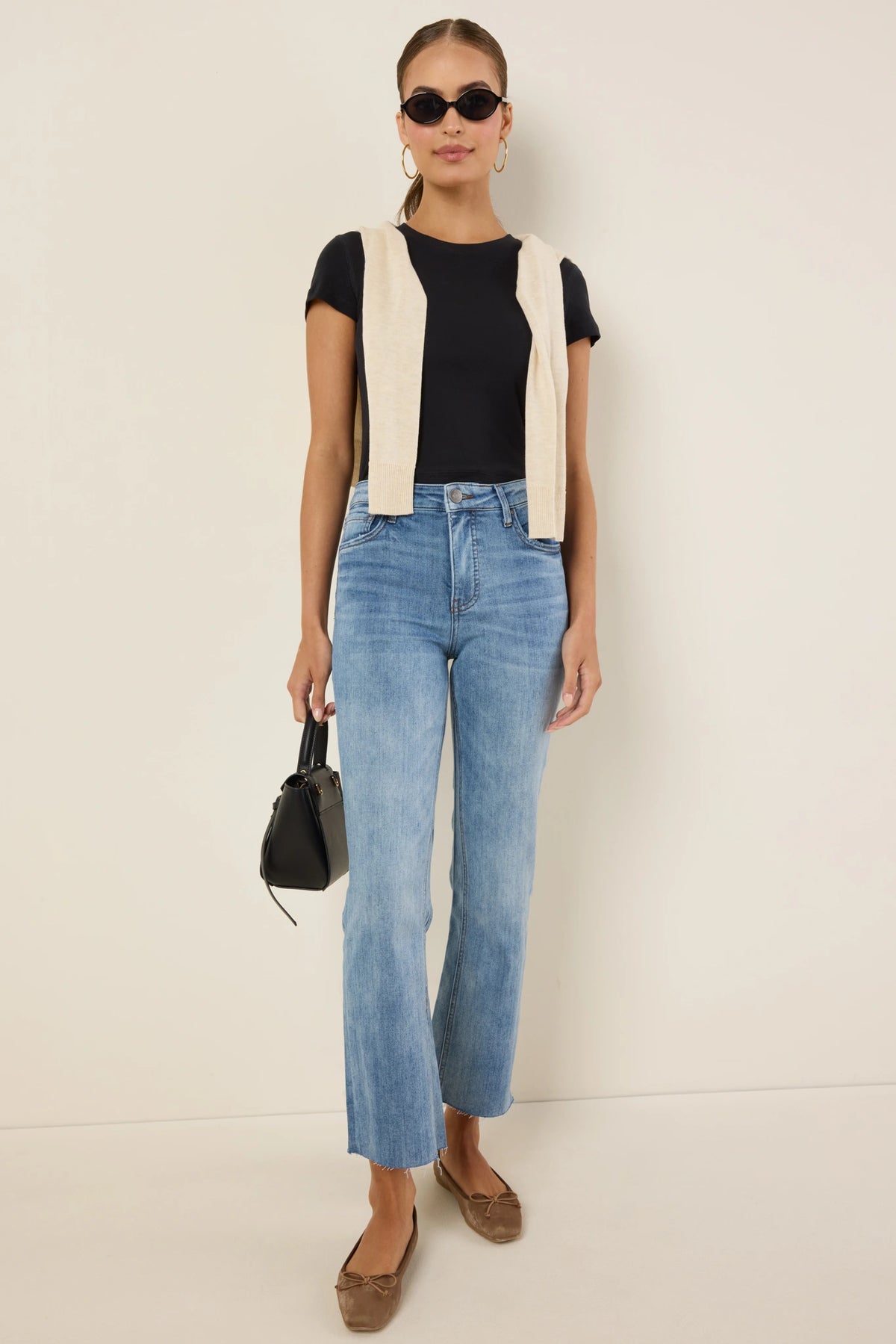 Kelsey Medium Wash Kick Flare Jeans - Styled Look, black tee, cream sweater vest, tan flats | Avara