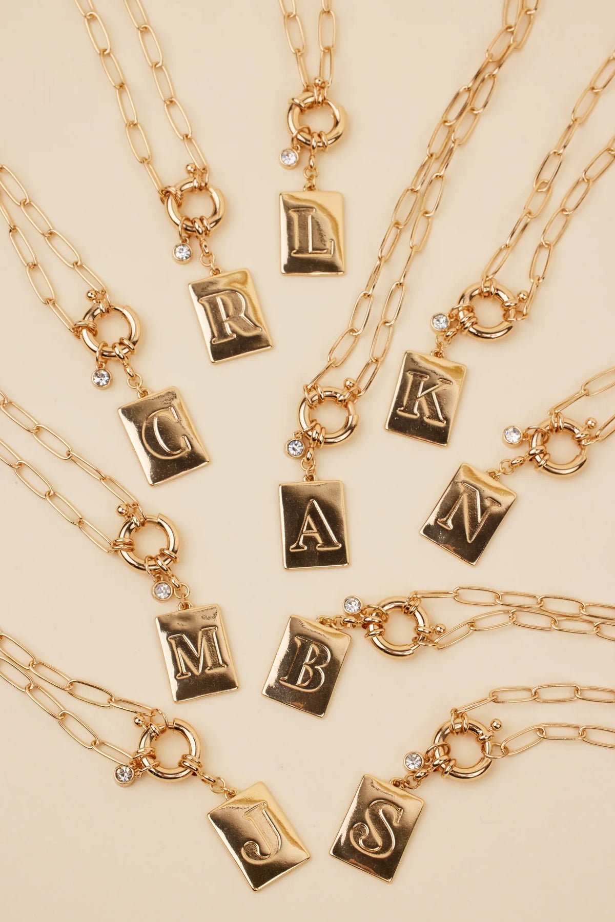Gold Initial Charm Necklace flat lay showing all letter options on paper-clip chains with rhinestone detail | Avara