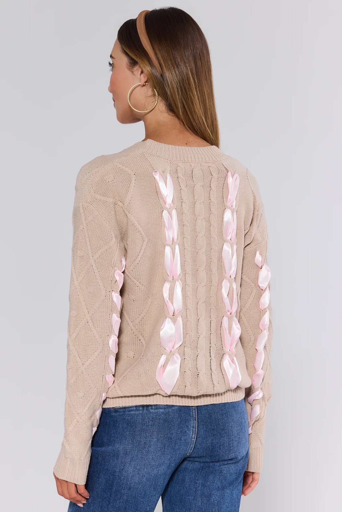 Beige Emerson Cable Knit Bow Sweater, full back view showing pink satin ribbon detail, paired with jeans | Avara
