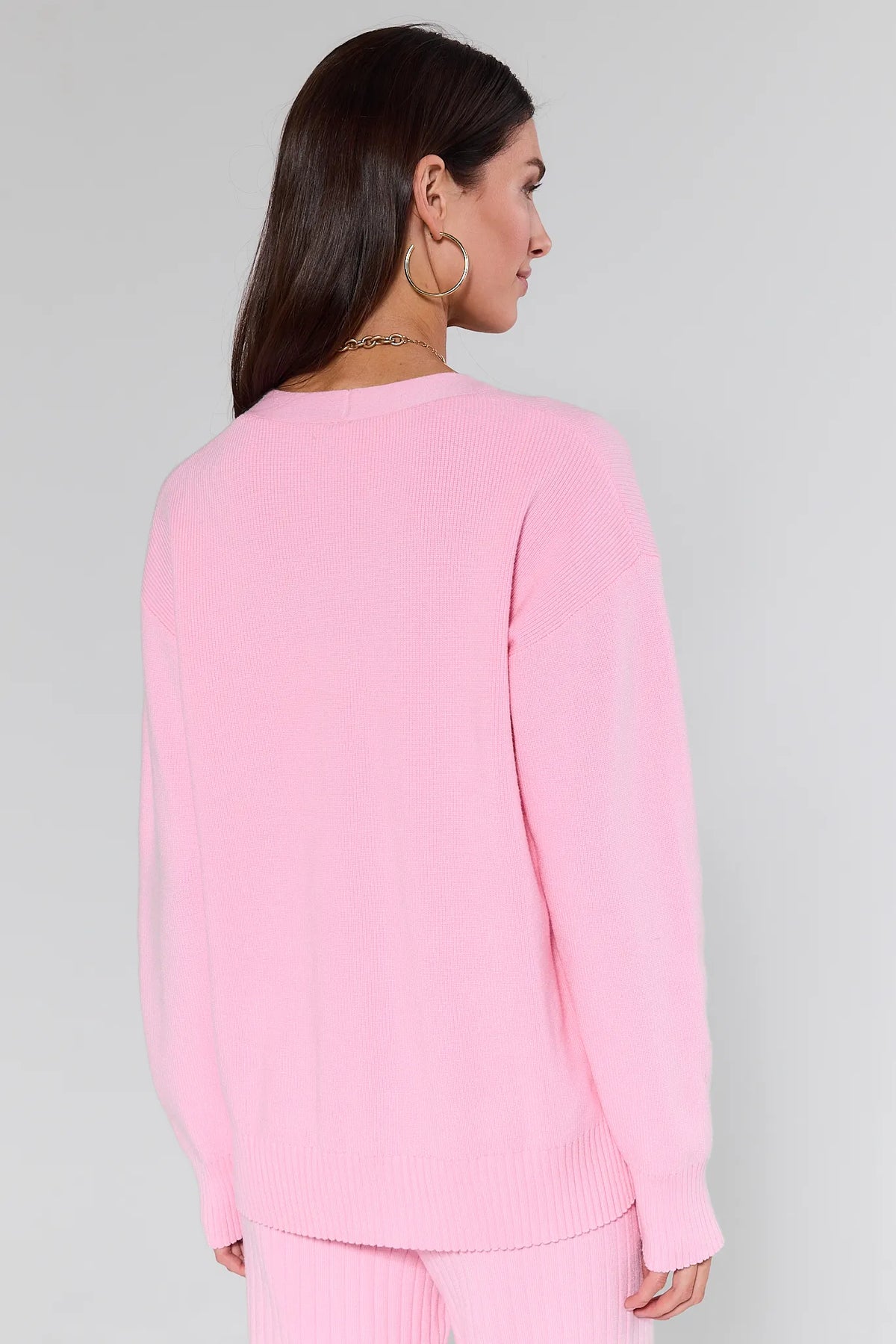 Woman wearing a Brianna Pink Knit Cardigan with gold buttons on a gray background