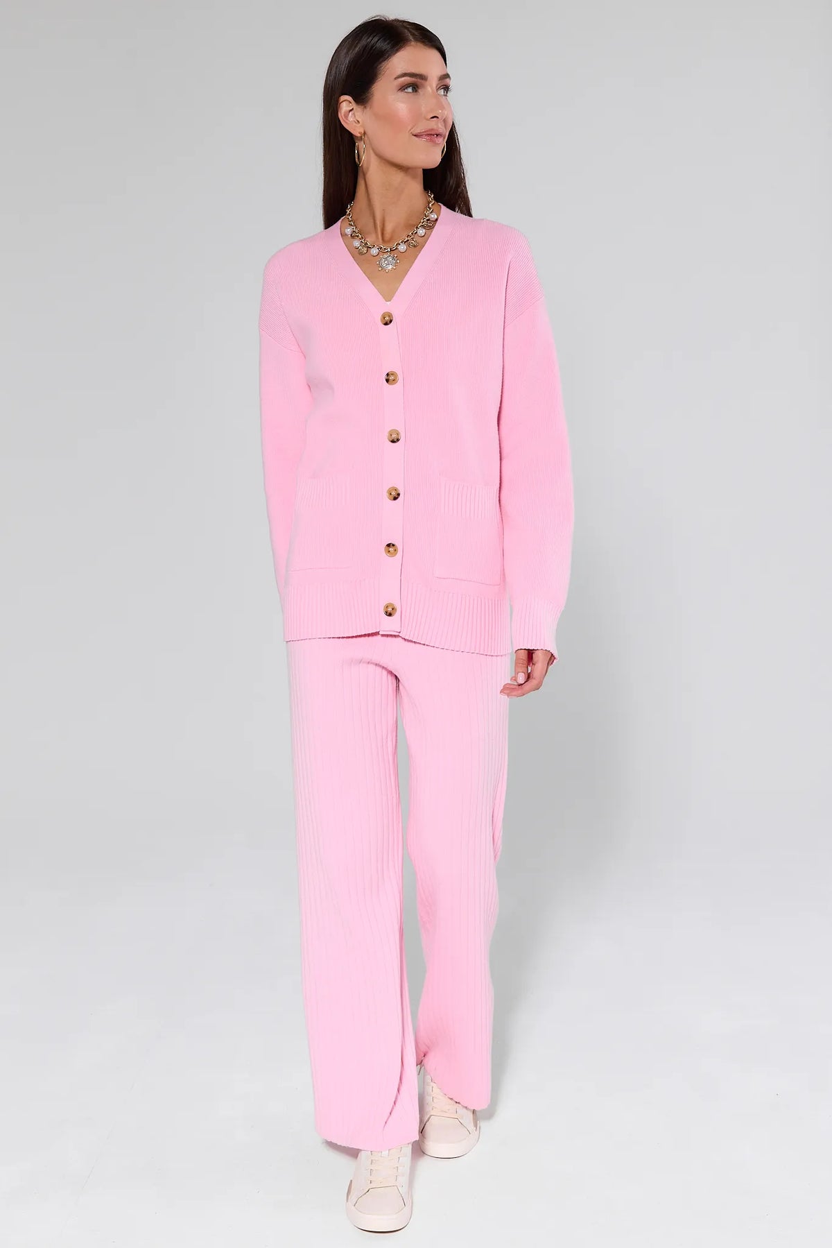 Woman wearing a Brianna Pink Knit Cardigan with gold buttons on a gray background