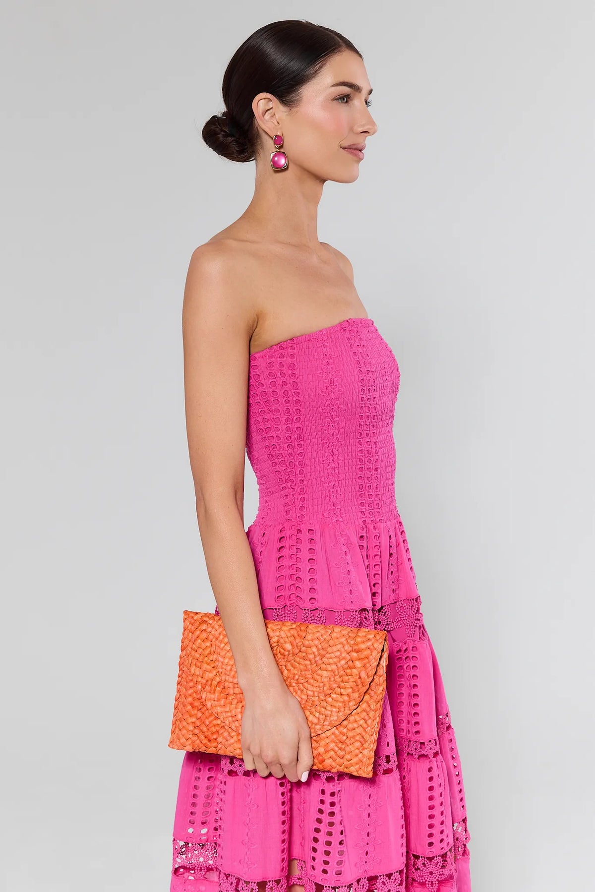Woman in pink eyelet dress holding orange woven clutch - Side Styled Look | Avara