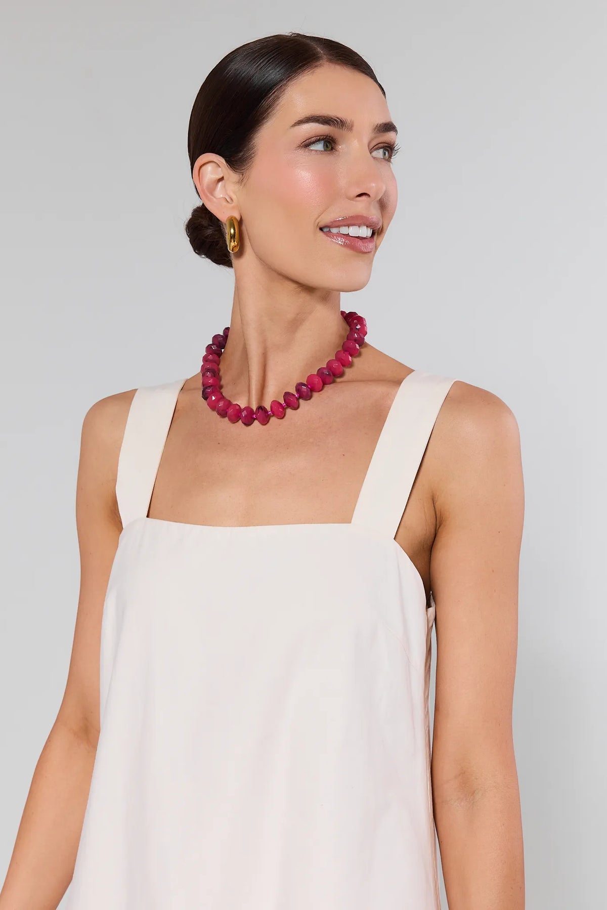 Woman wearing Melody Bone Eyelet Midi Dress, featuring a square neckline, sleeveless design, and chunky pink beads against a neutral background.