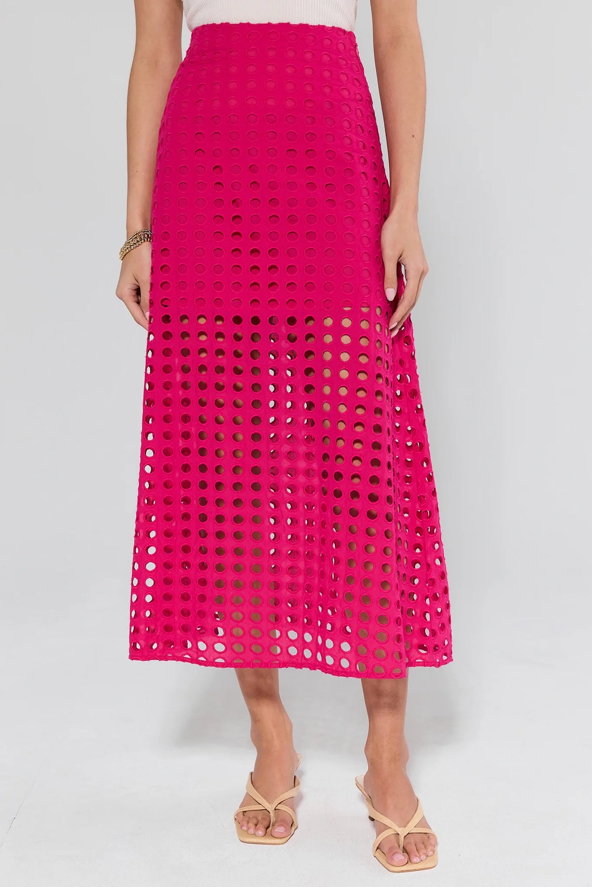 Ellie Pink Eyelet Midi Skirt modeled with a white tank, beige sandals, featuring a high-rise A-line silhouette with circular cutouts, perfect for versatile styling.