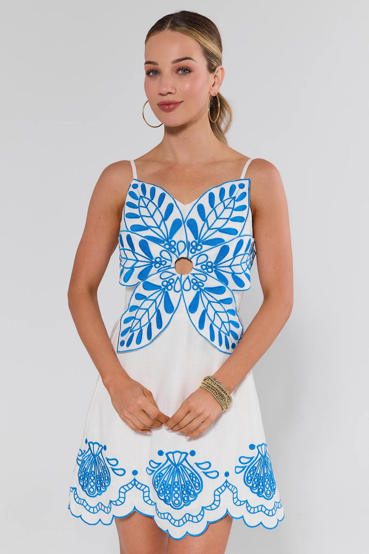 Woman wearing a white dress with blue floral patterns on a plain background