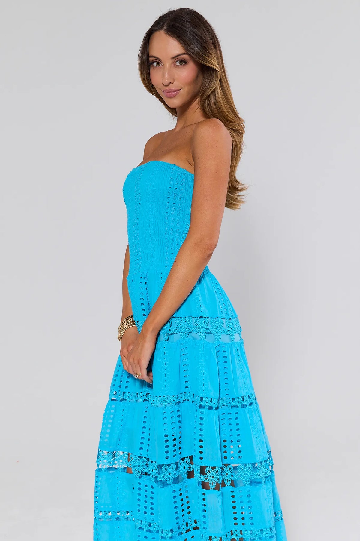 Woman wearing Cecilia Blue Strapless Midi Dress with eyelet embroidery and tiered skirt - Side View | Avara