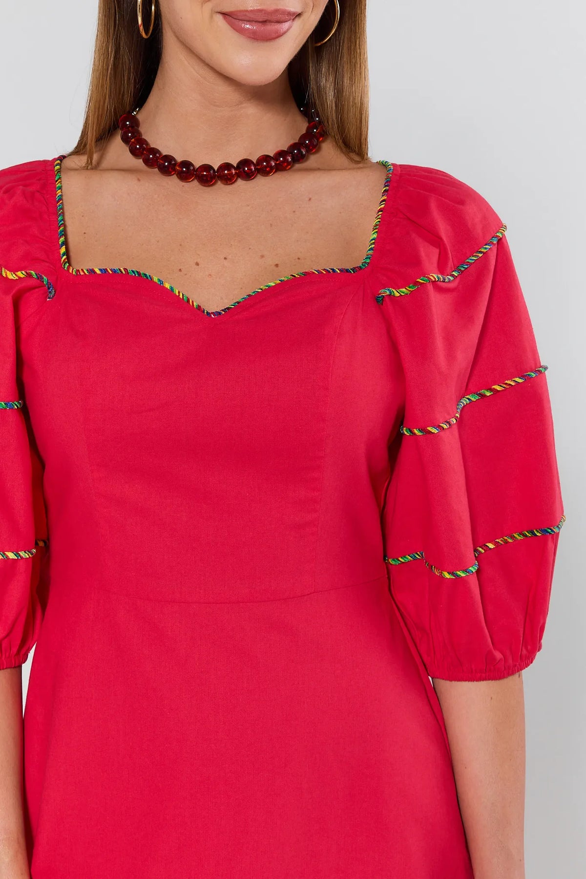 Red puff sleeve dress sweetheart neckline with rainbow striped piping detail close-up - On Model | Avara