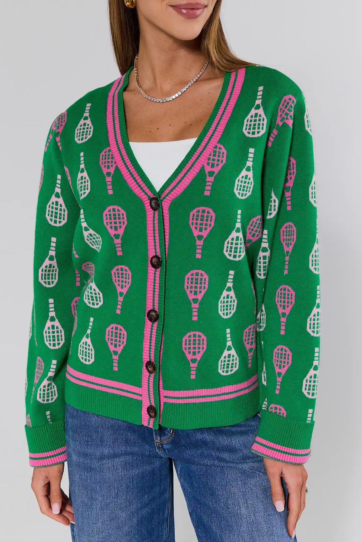 Green racket print cardigan with pink stripe trim, close-up front detail, button closure | Avara