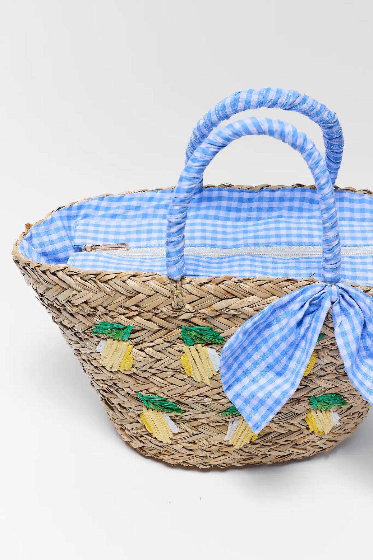 Close up of Gentry Woven Raffia Lemon Bag showing blue gingham lining, zip closure, and lemon embroidery | Avara