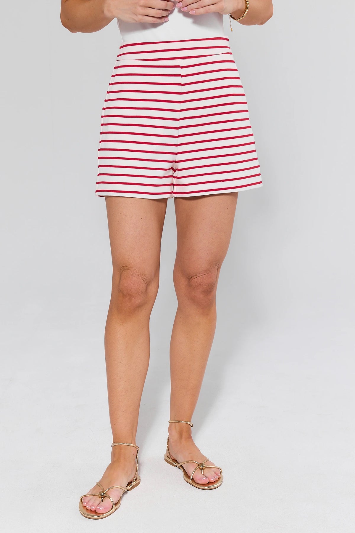 Women's red and white striped shorts styled with gold sandals, front view on model | Avara