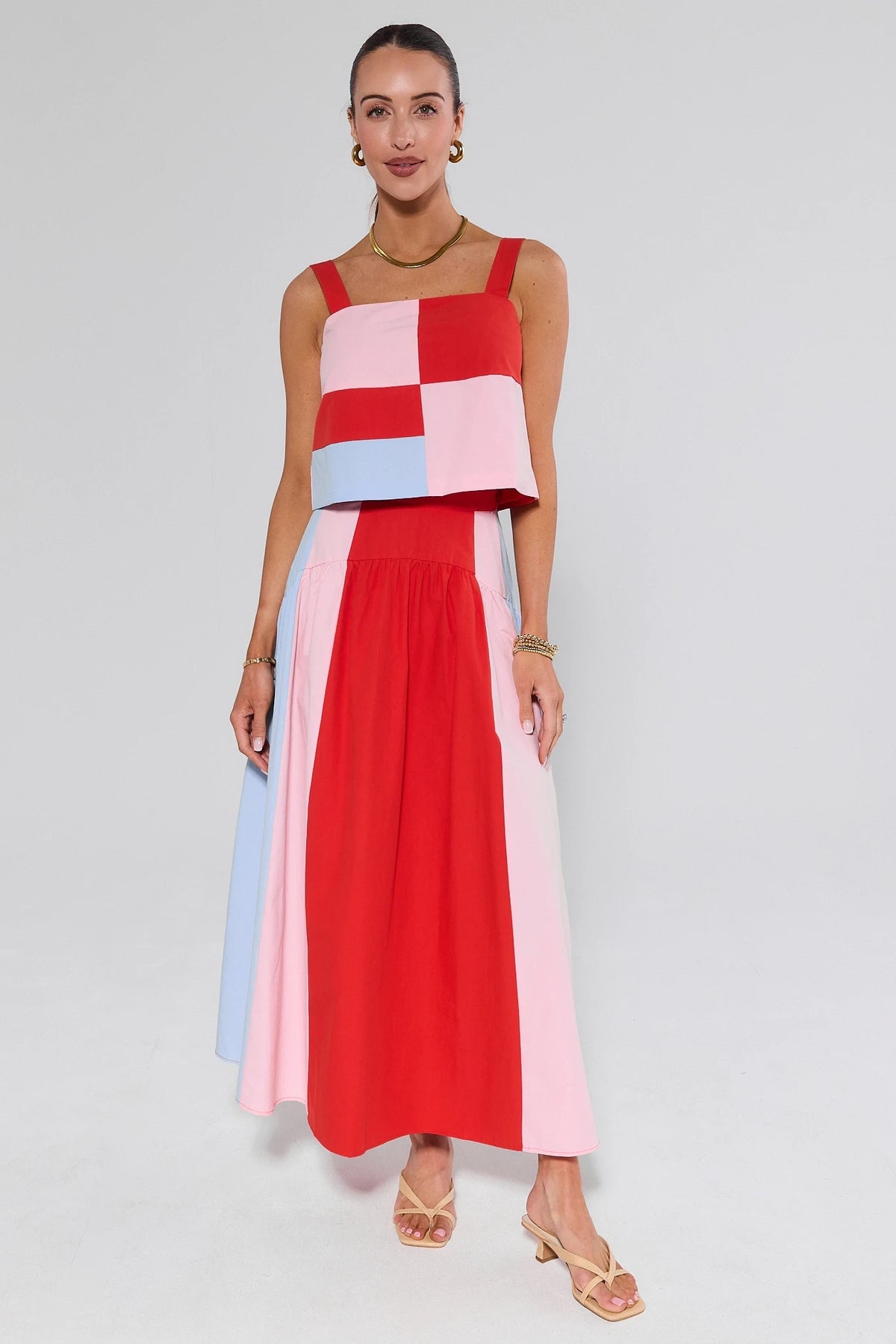 Woman wearing a colorful checkered dress on a plain background