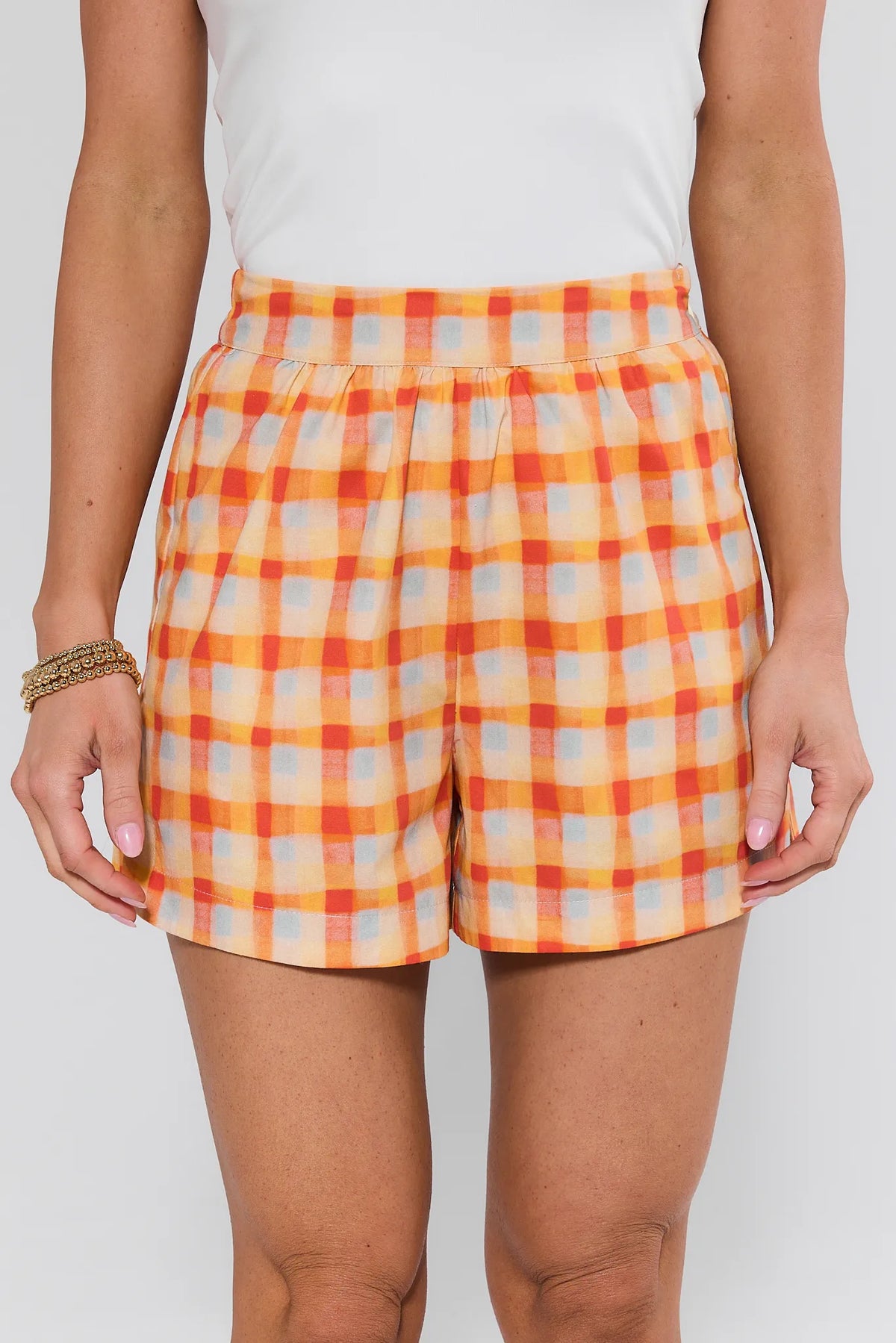 Person wearing orange and beige checkered shorts on a white background