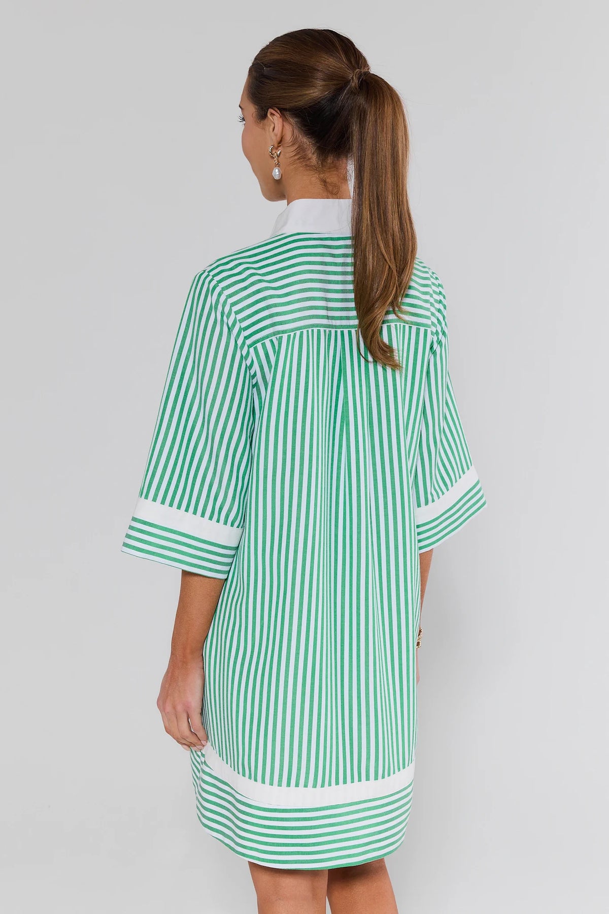 Woman wearing a green and white striped dress on a plain background