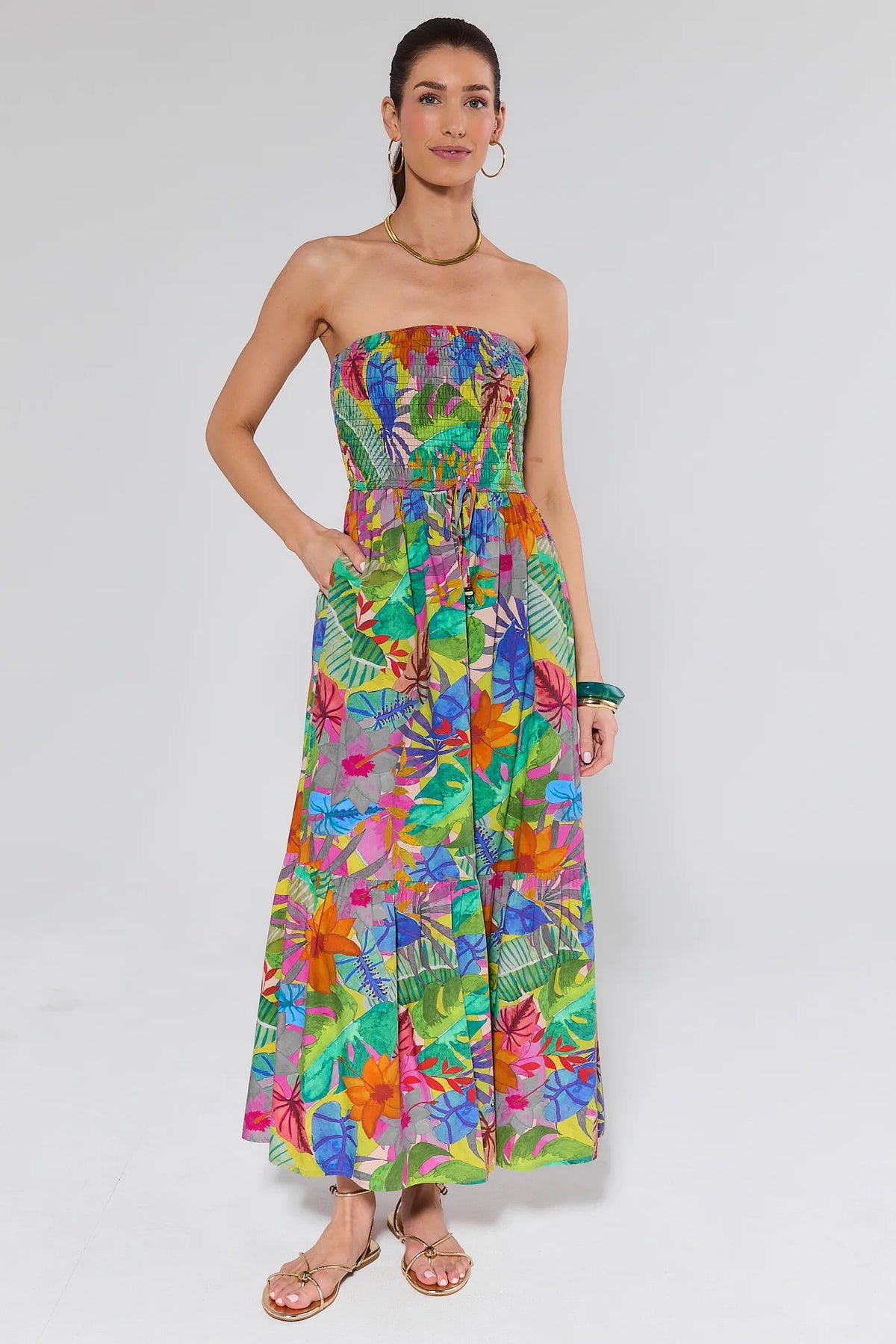 Woman wearing a colorful strapless dress with a leaf pattern on a white background