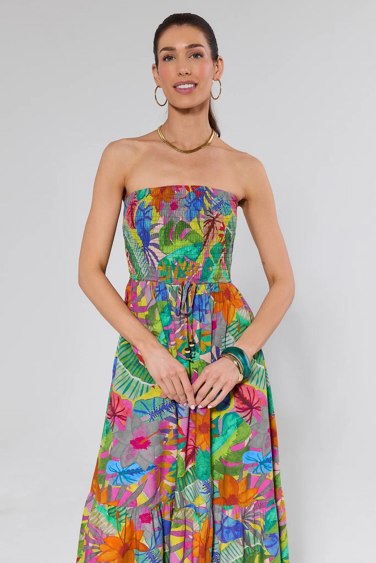 Woman wearing a colorful strapless dress with a floral pattern on a white background