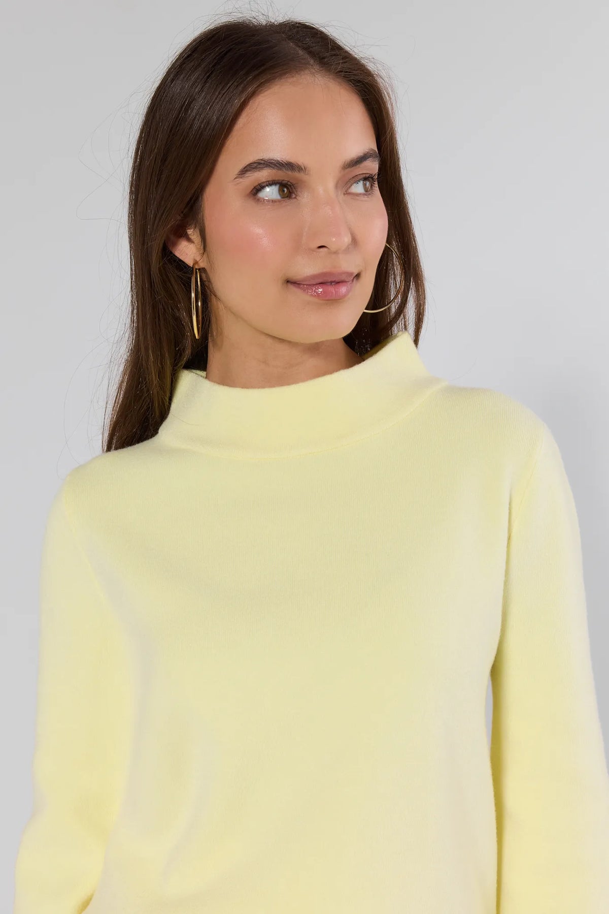 woman wearing a yellow sweater on a white background