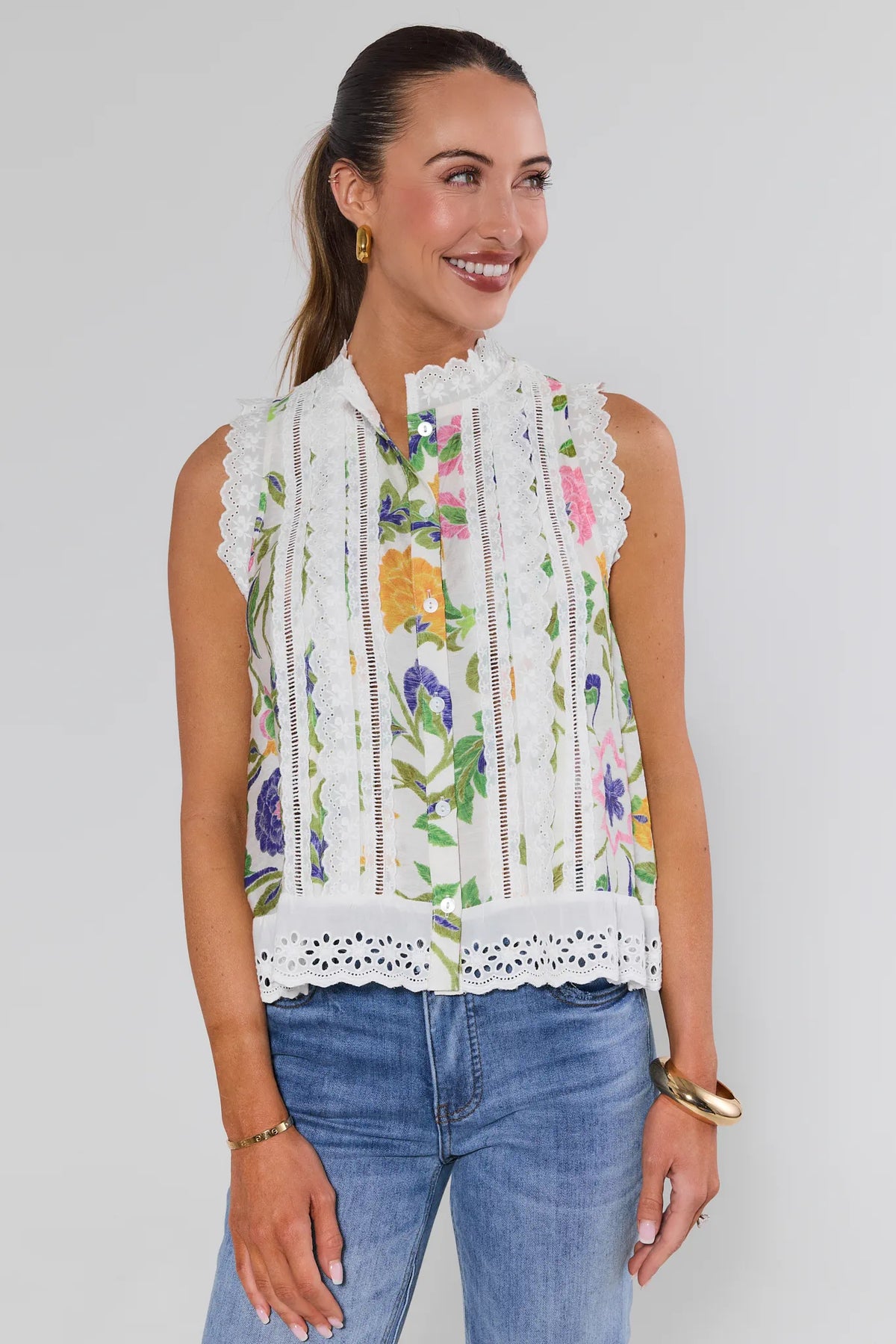 Woman wearing a sleeveless floral top with lace details against a plain background