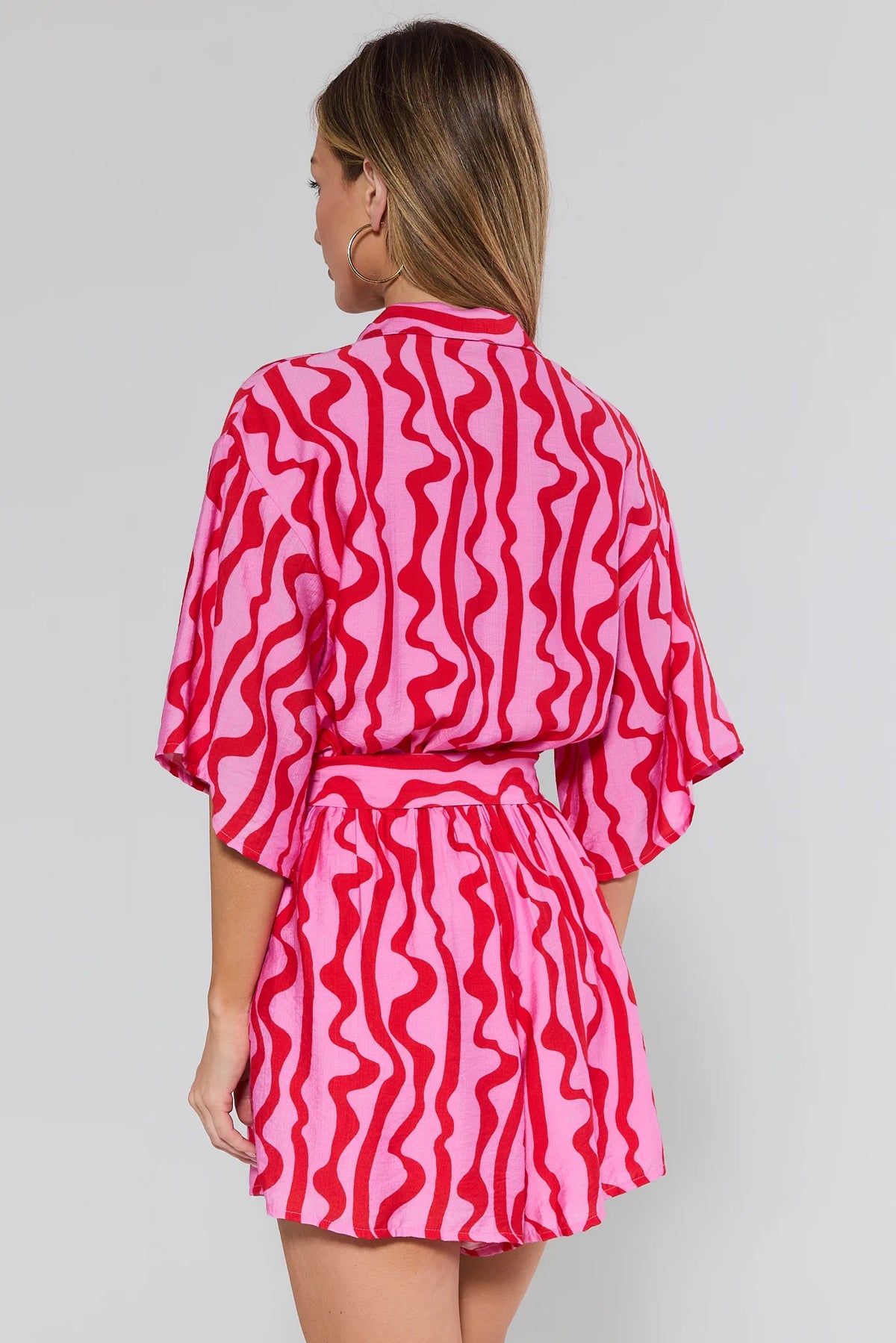 Woman wearing a pink and red patterned outfit on a gray background