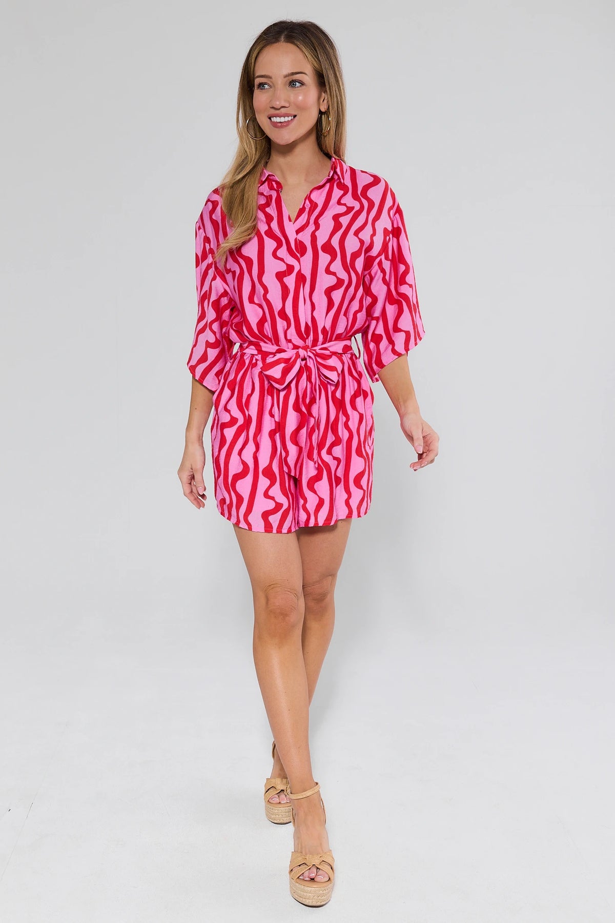 Woman wearing a pink and red patterned dress on a white background