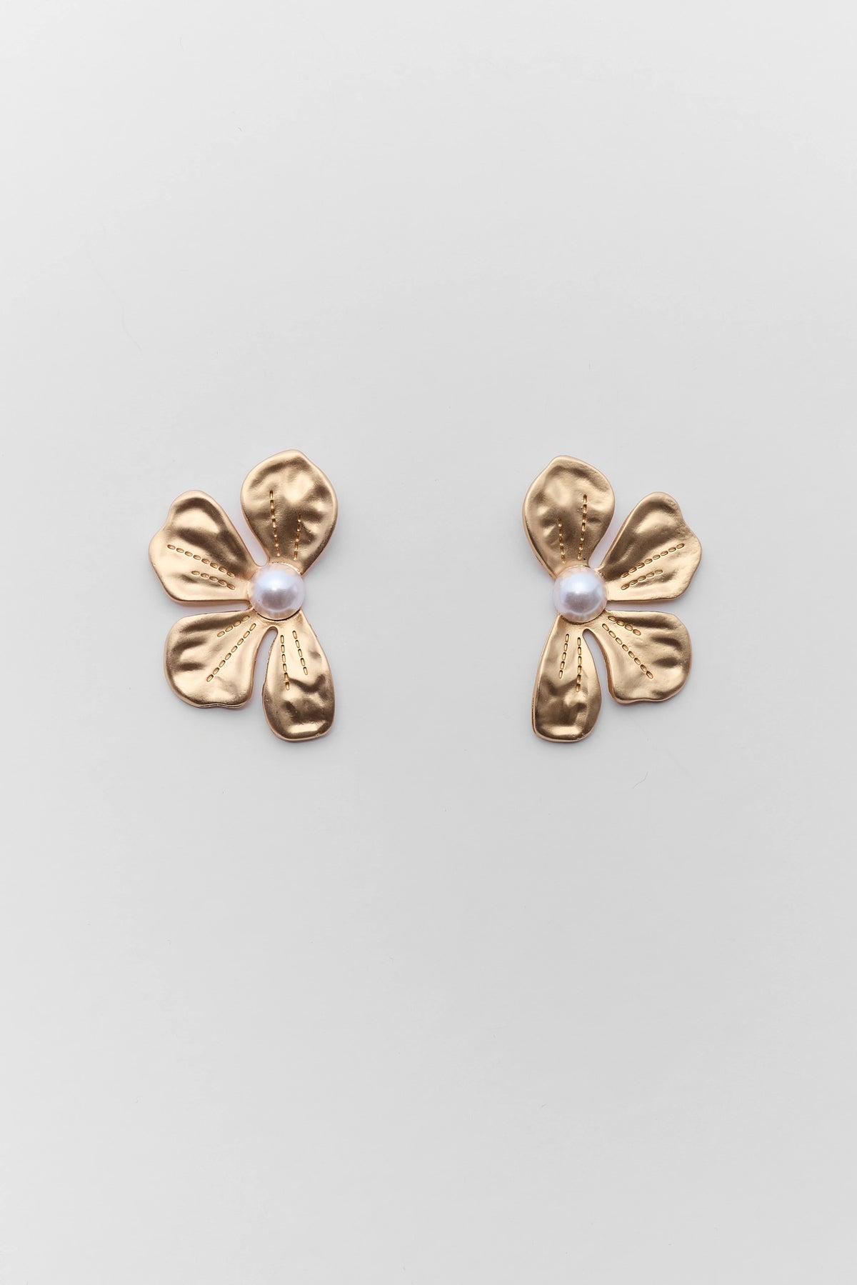 Gold flower-shaped earrings with pearl centers on a light gray background