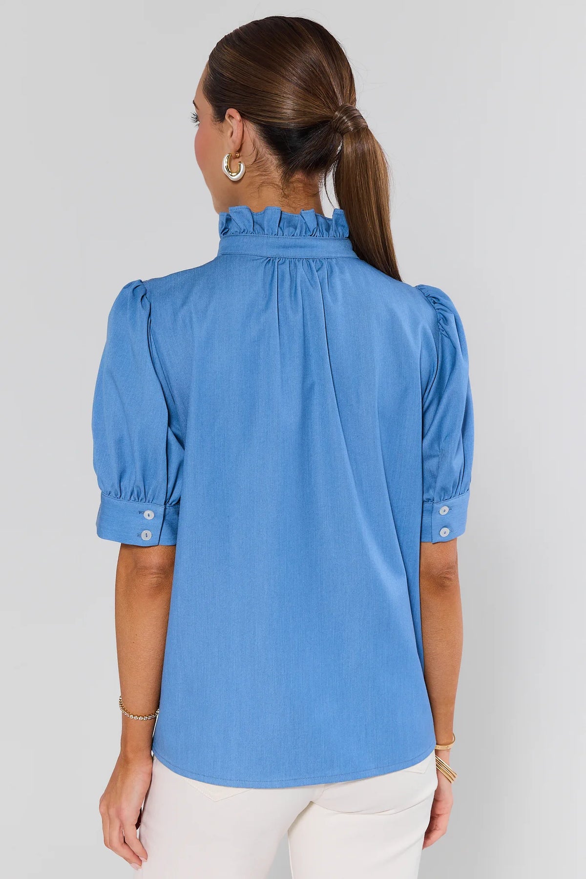 Woman wearing a blue blouse with puffed sleeves on a plain background