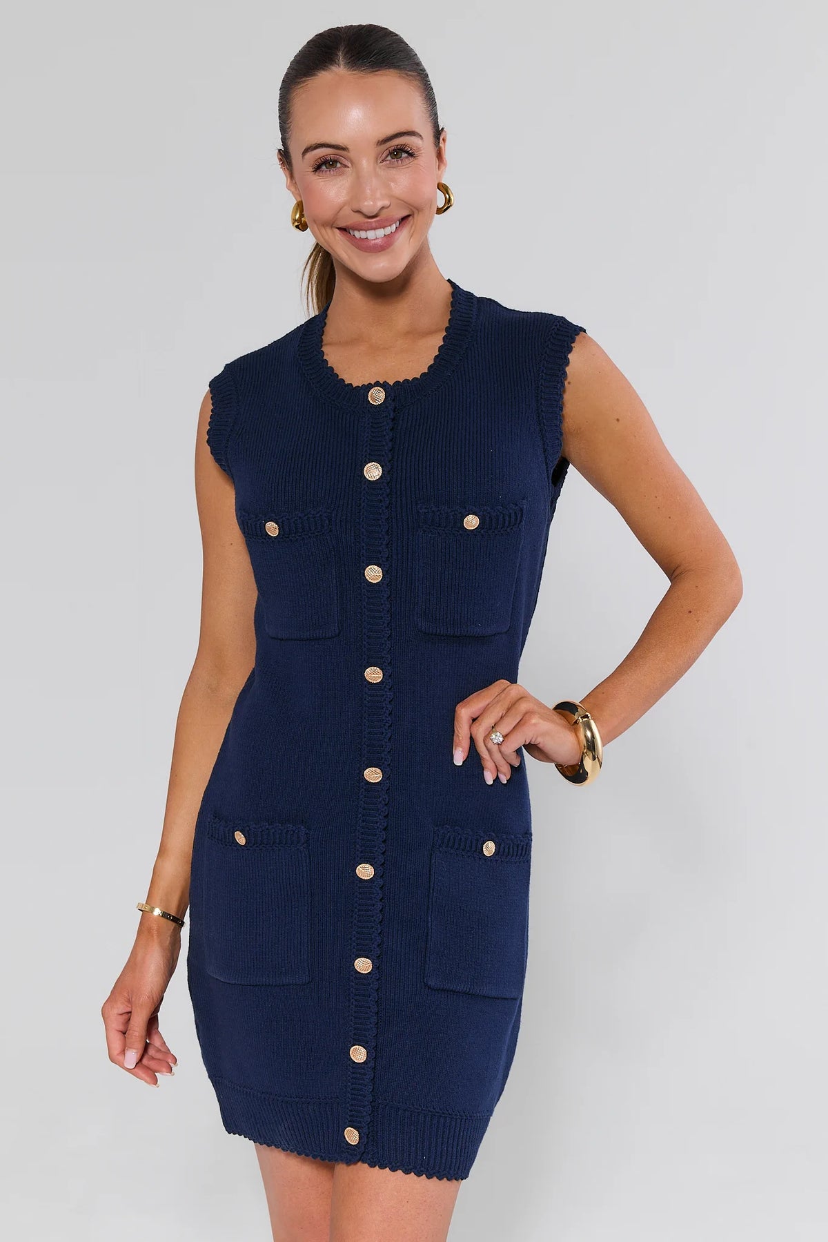 Woman wearing navy blue knit mini dress with gold buttons and scalloped trim - Front View | Avara