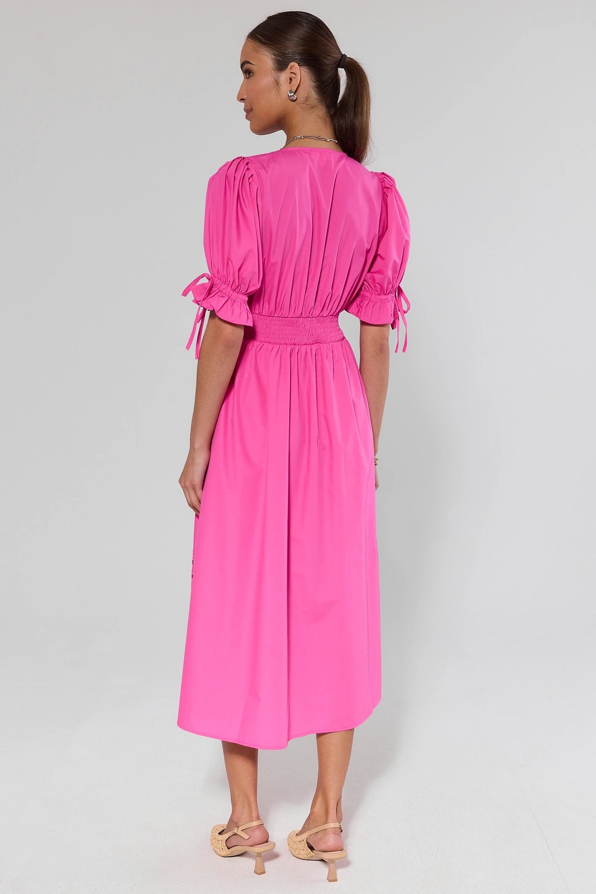 Woman wearing a pink dress with puff sleeves on a white background
