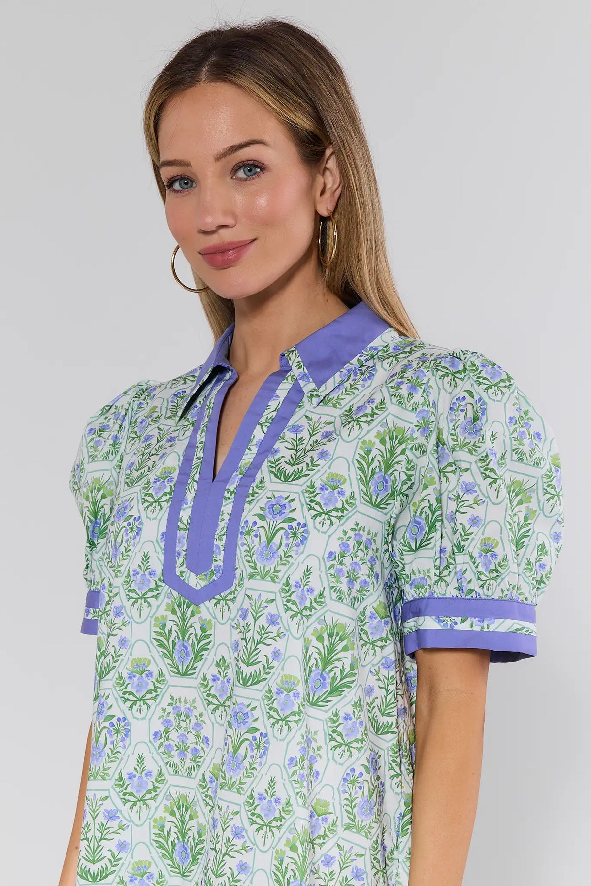 Woman wearing a floral dress with purple accents against a plain background