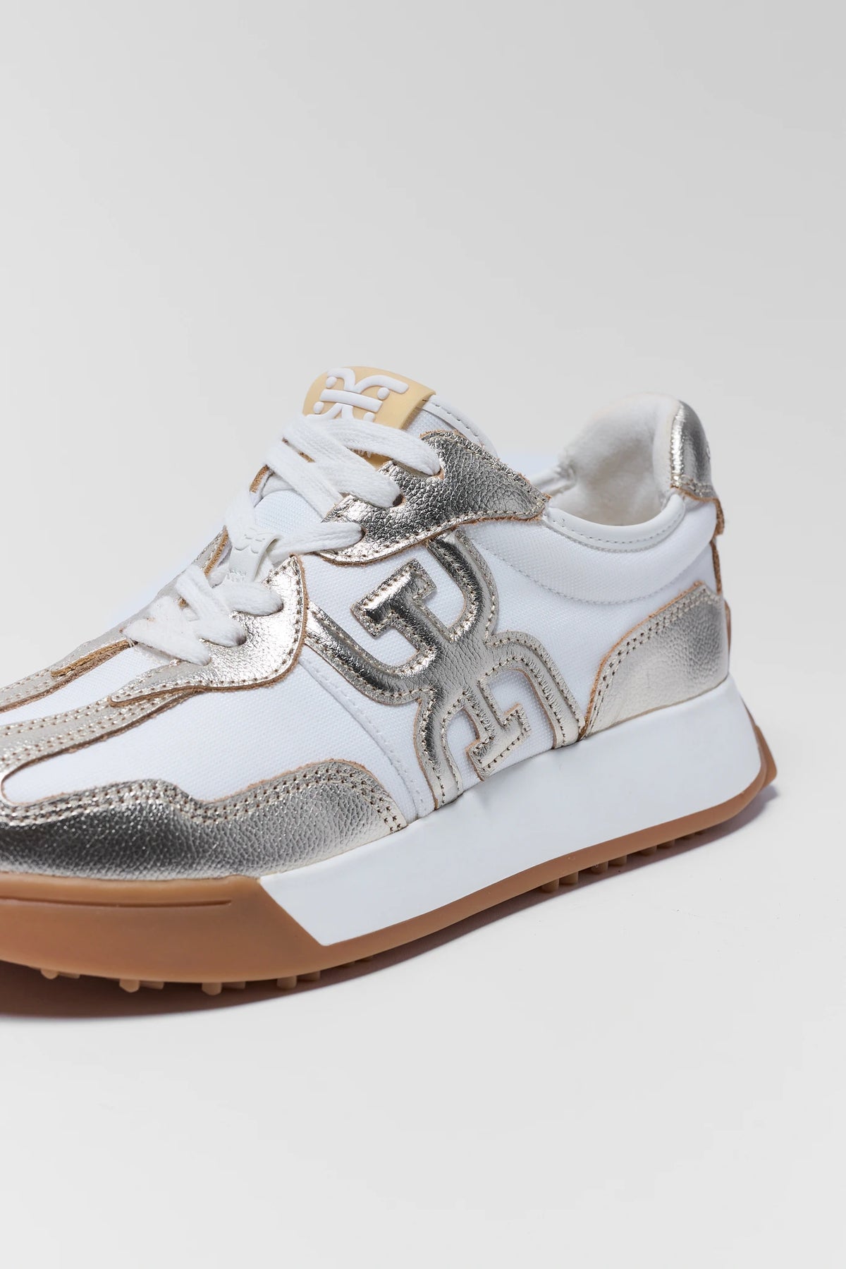 Sam Edelman Langley Gold sneaker close-up showing metallic logo detail and white laces | Avara