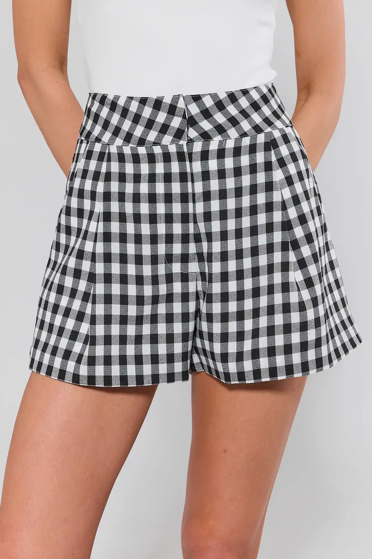 Black gingham tailored shorts, close-up front view showing high waist and pleat detail | Avara