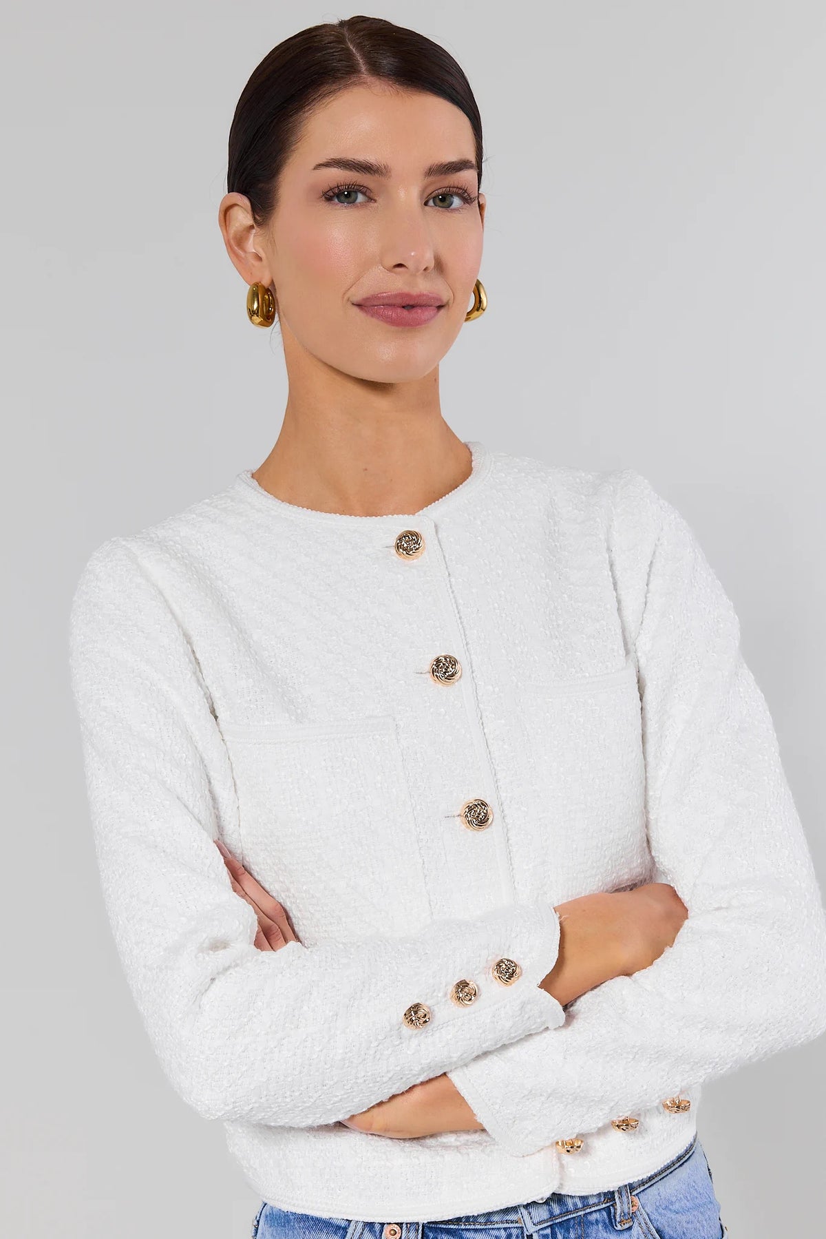 Woman wearing white tweed cardigan with gold button-front detail, arms crossed - Close-Up View | Avara