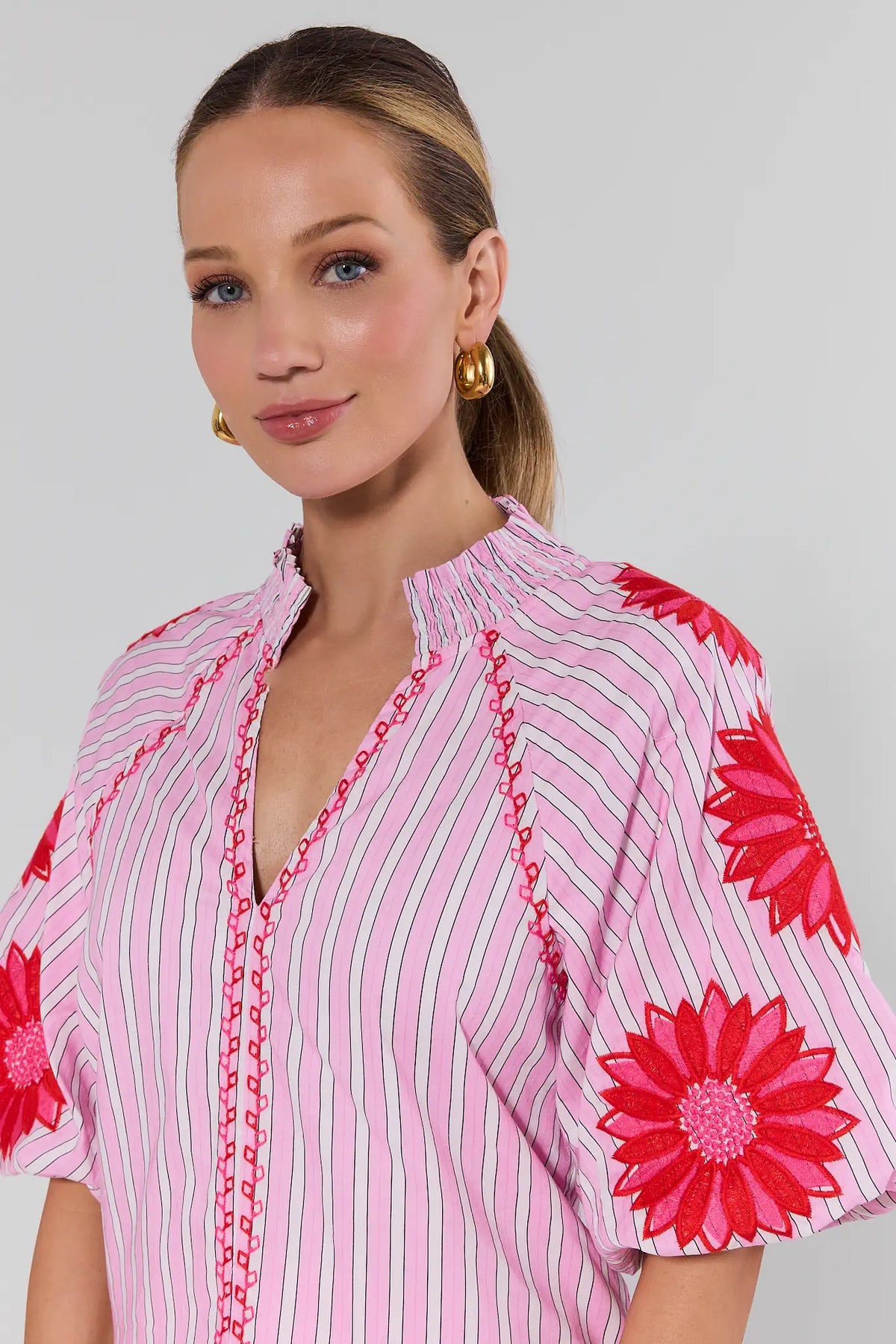Close-up of pink striped embroidered top with red daisy appliqué sleeves and smocked neckline - THML Krista Top | Avara