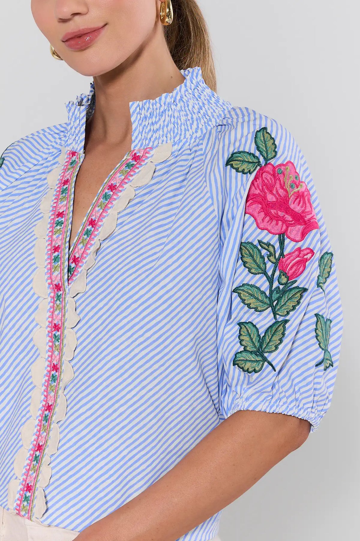Close-up of blue striped floral embroidered top showing rose sleeve detail and scalloped placket trim | Avara