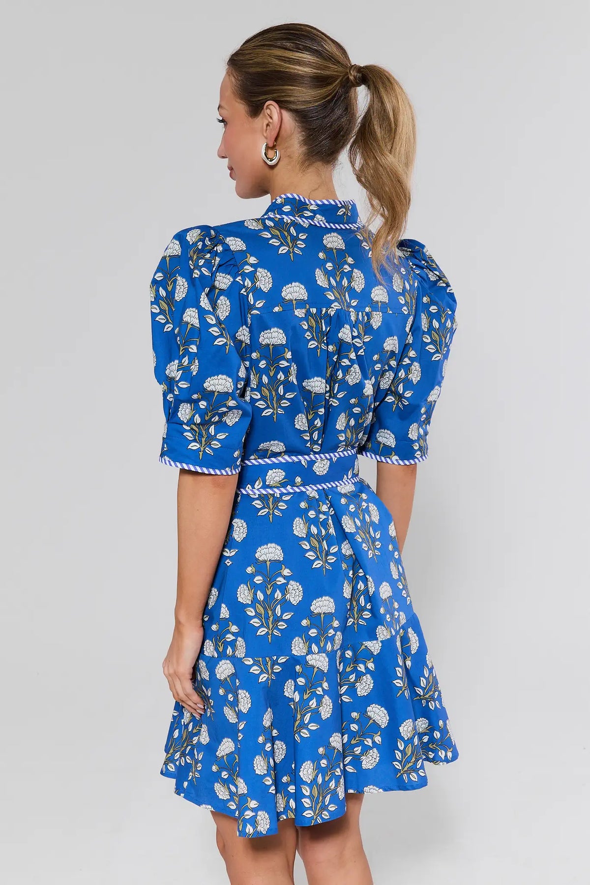 Woman wearing a blue floral dress against a plain background