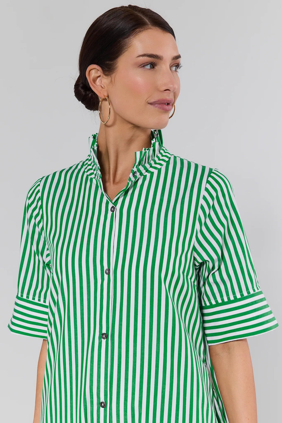 Close-up of ruffle neckline and cuffed sleeves on green striped midi dress, upper body detail | Avara
