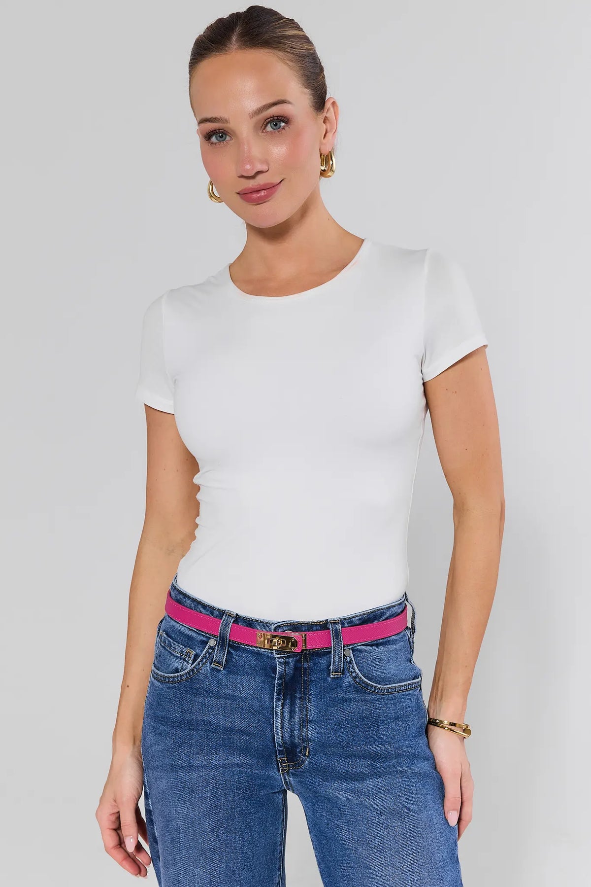 Woman styling Piper Pink Faux Leather Belt with white tee and blue jeans, gold hardware detail - On Model | Avara
