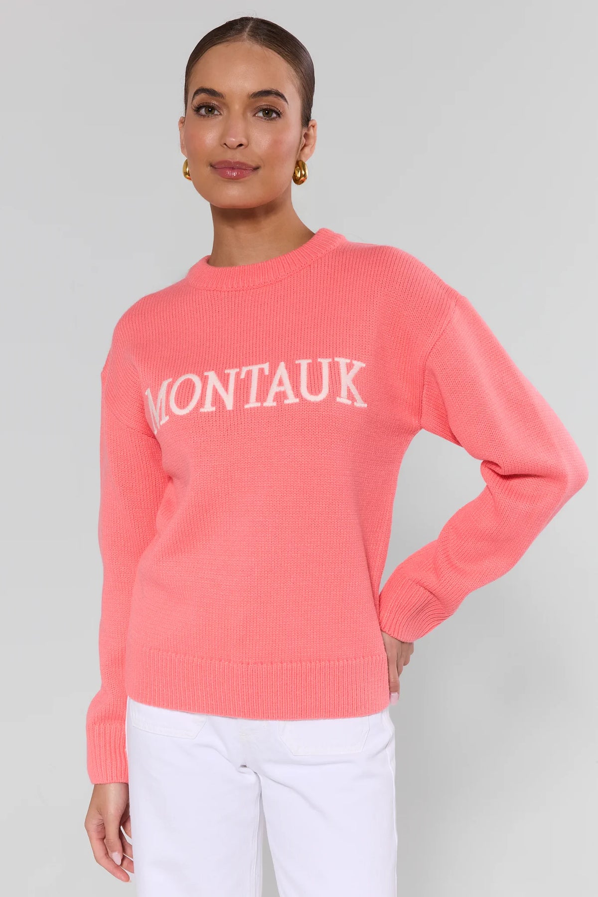 Coral knit sweater with 'Montauk' lettering styled with white wide-leg pants and sandals, full-length view | Avara