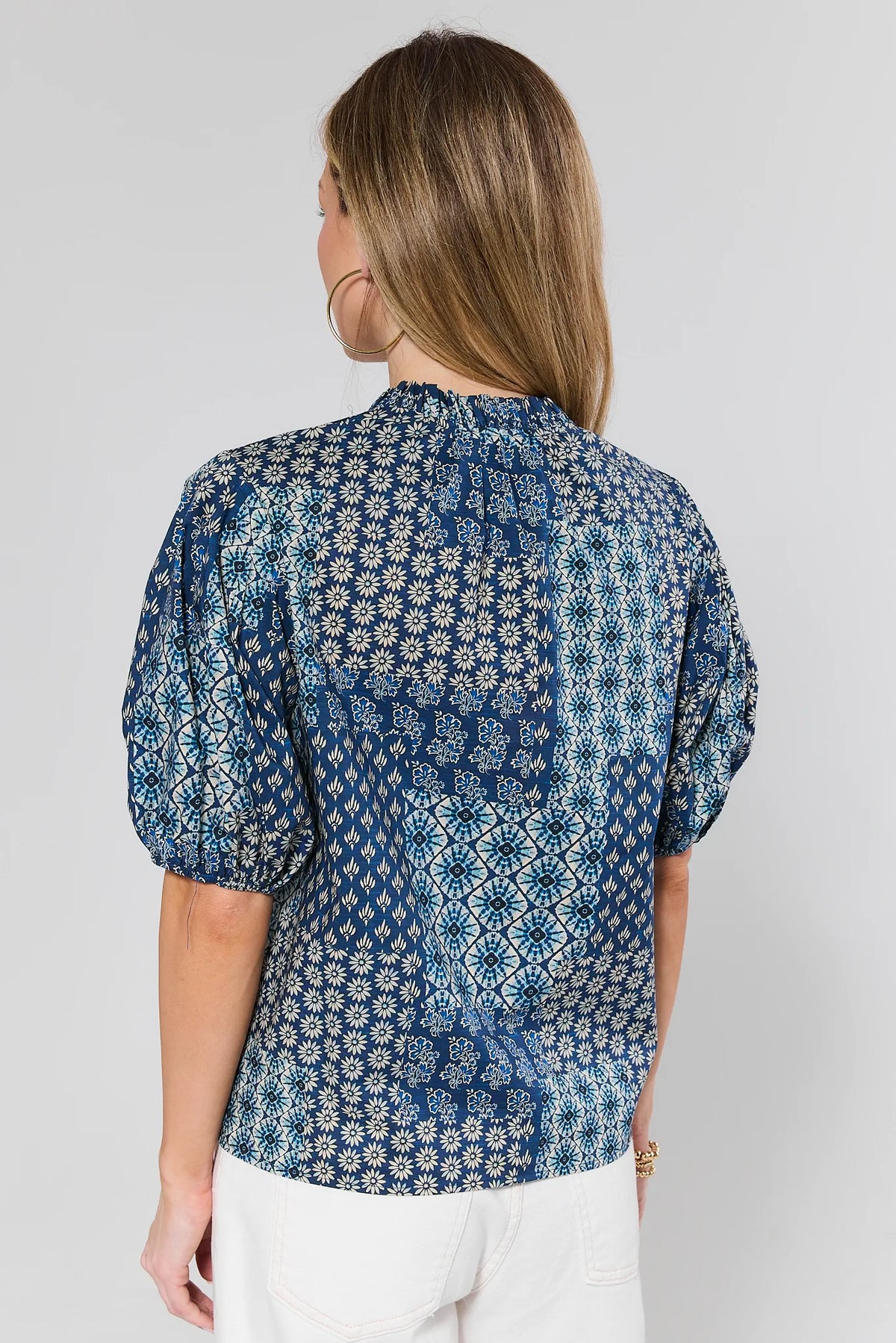 Woman wearing a blue patterned blouse against a gray background