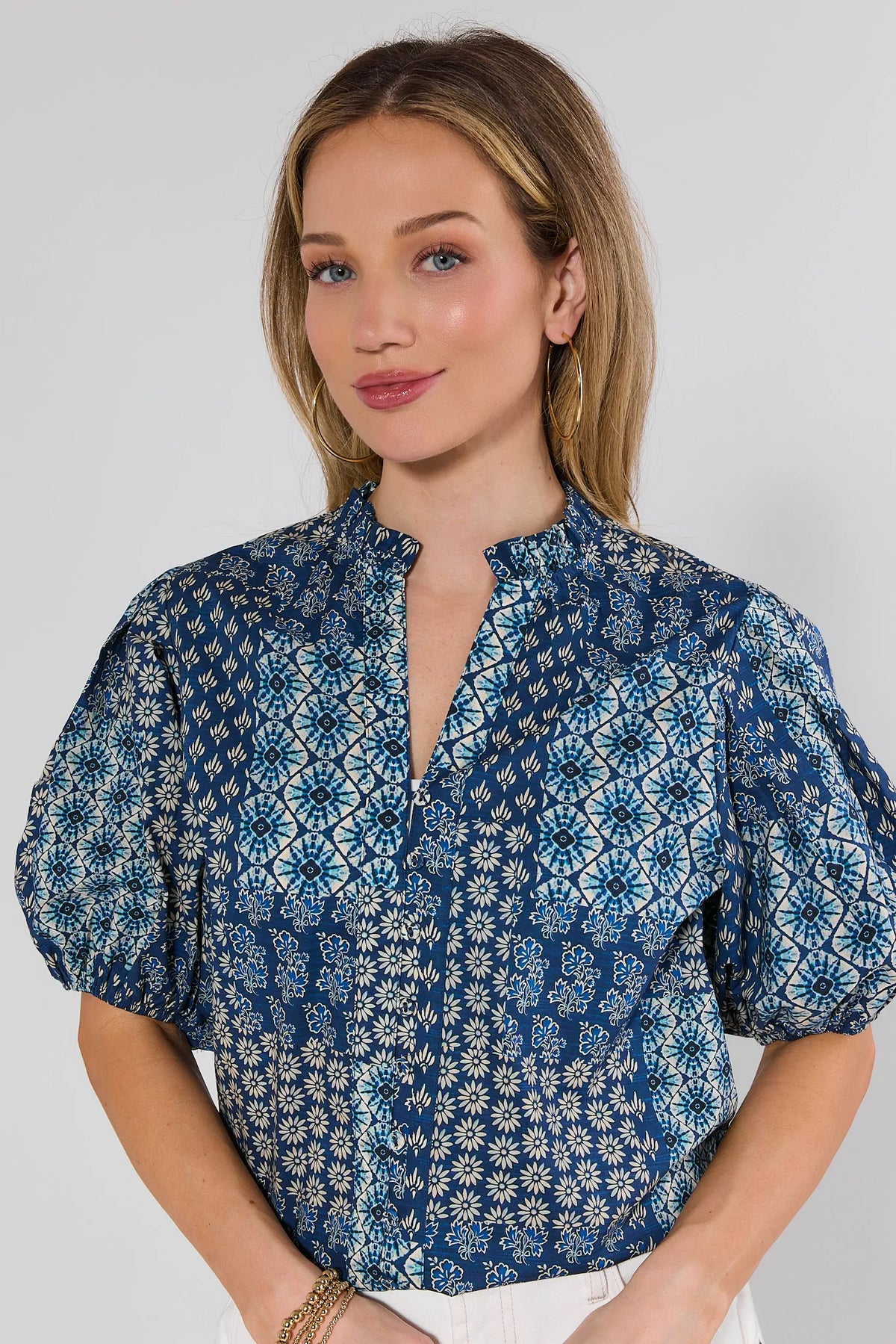 Woman wearing a blue patterned blouse against a plain background