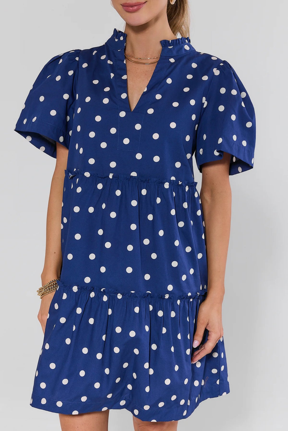 Evan Navy Polka Dot Short Dress - close-up of ruffle collar, v-neckline, and tiered ruffle waist detail | Avara