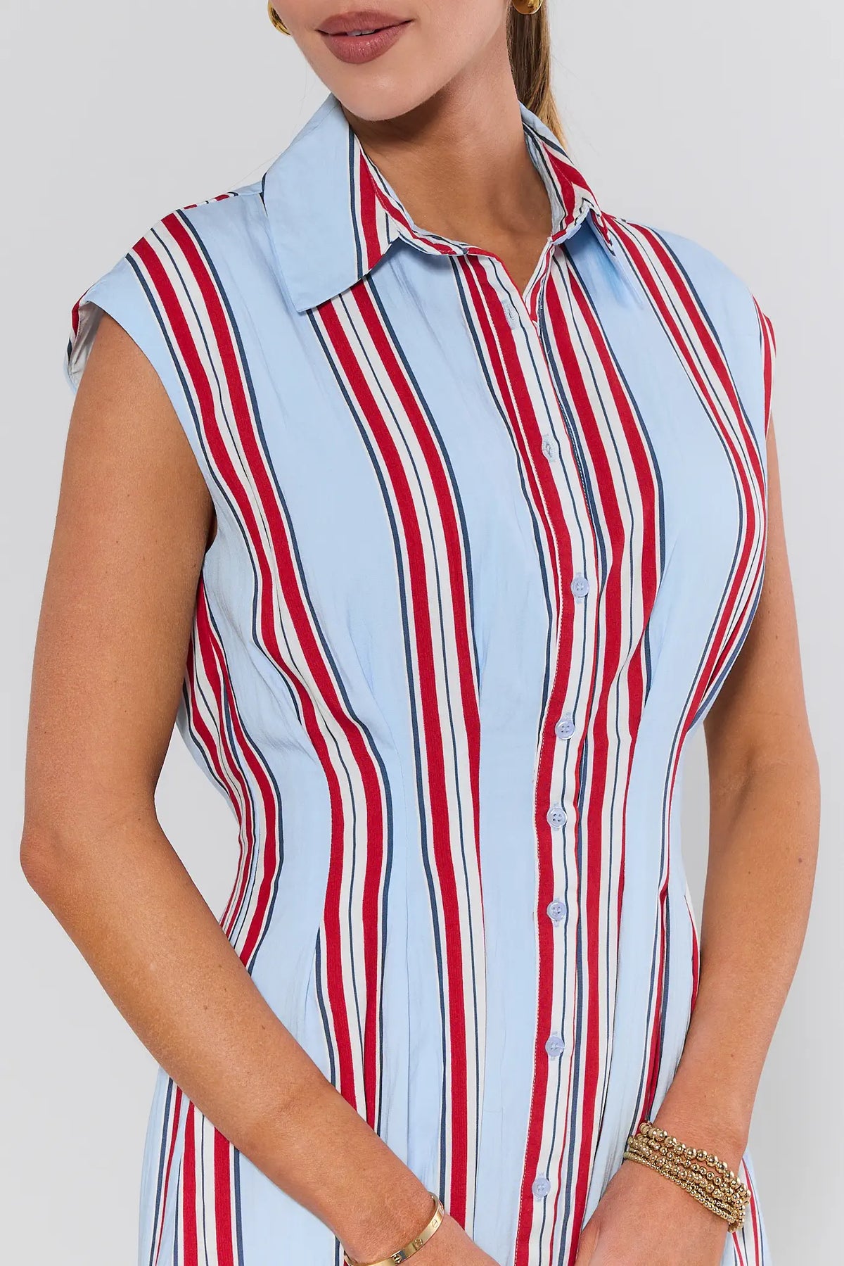 Woman wearing a sleeveless shirt with red and white vertical stripes on a plain background