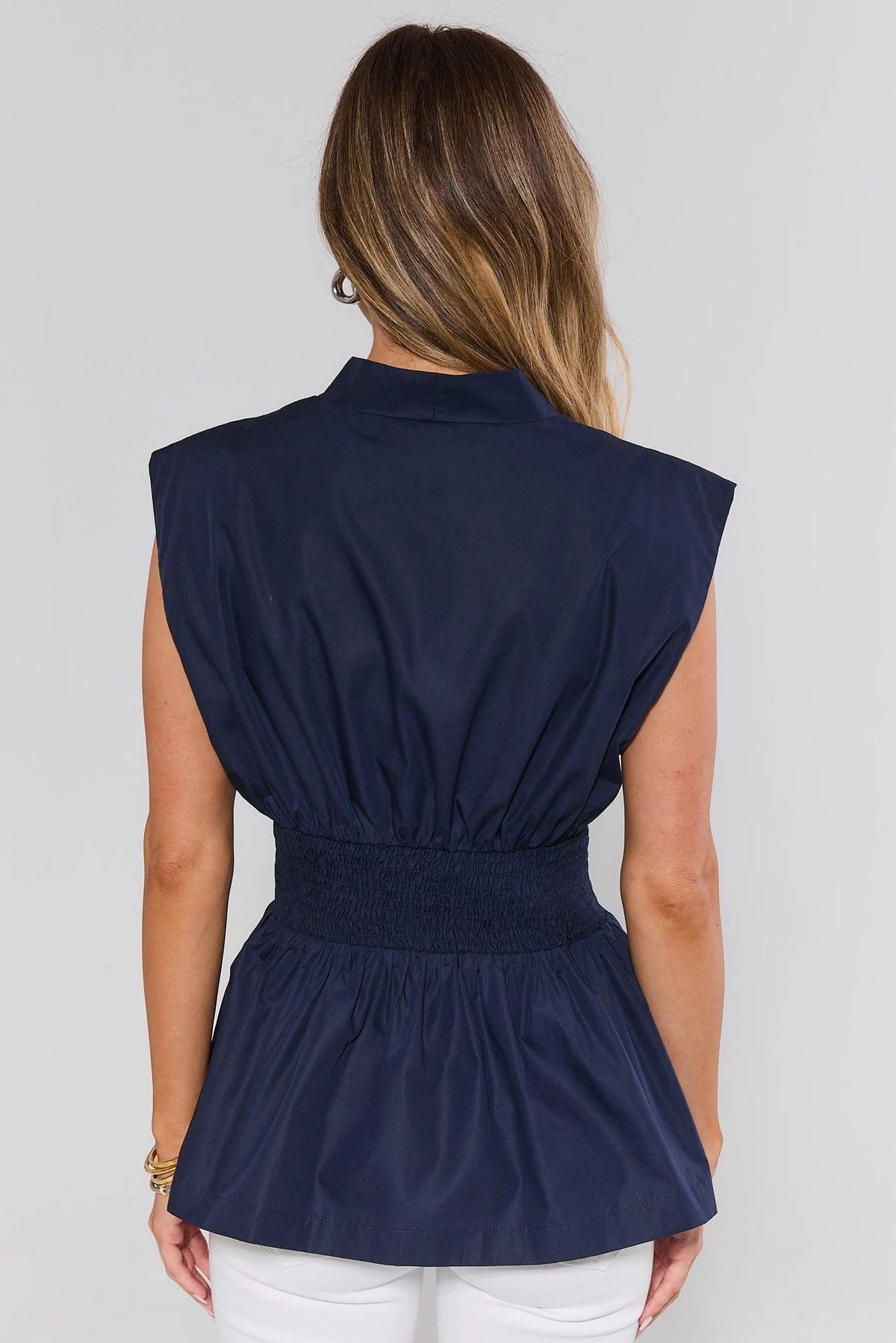 Navy zip-up peplum top back view showing smocked waist and gathered silhouette | Avara