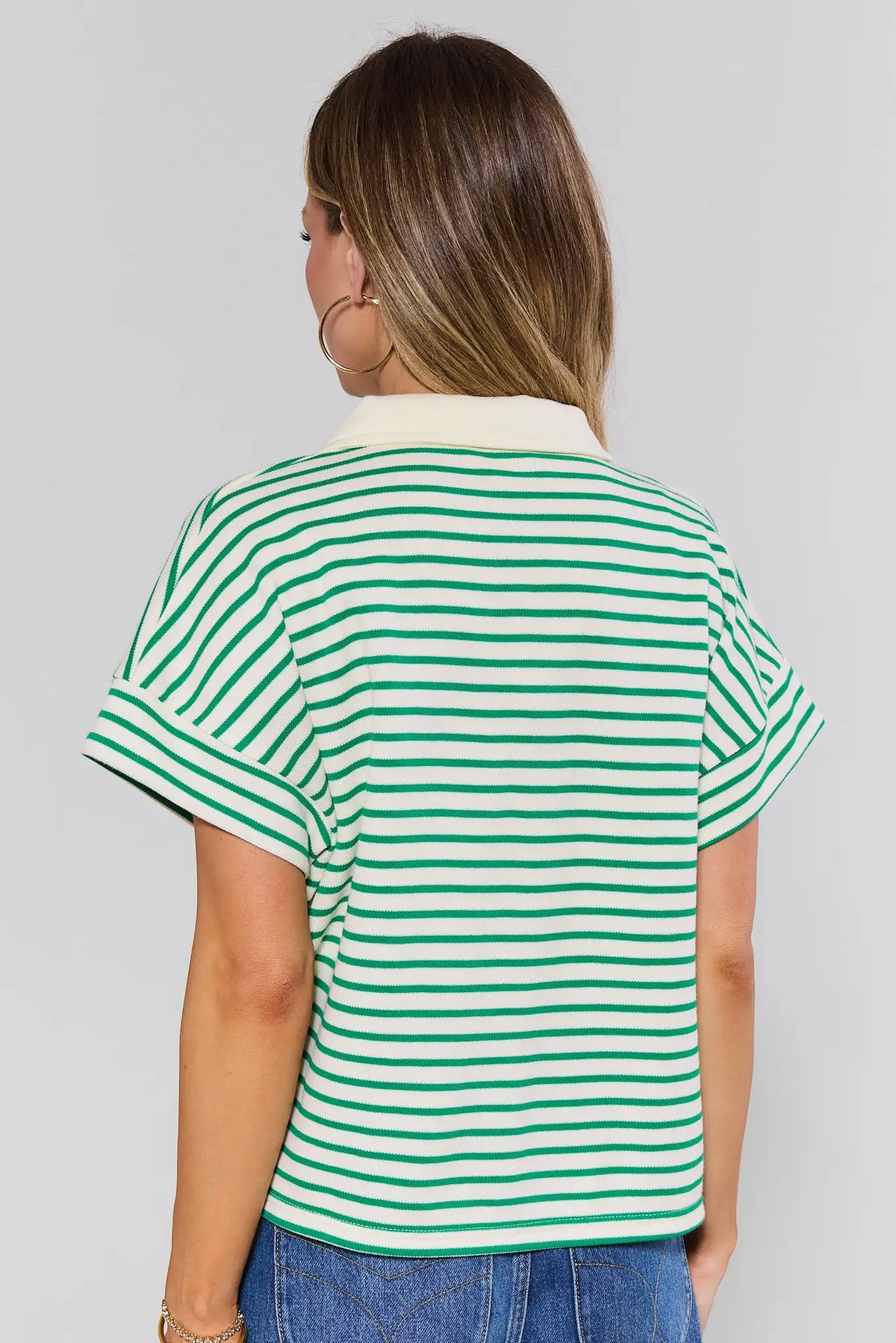 Woman standing wearing a green and white striped shirt against a gray background