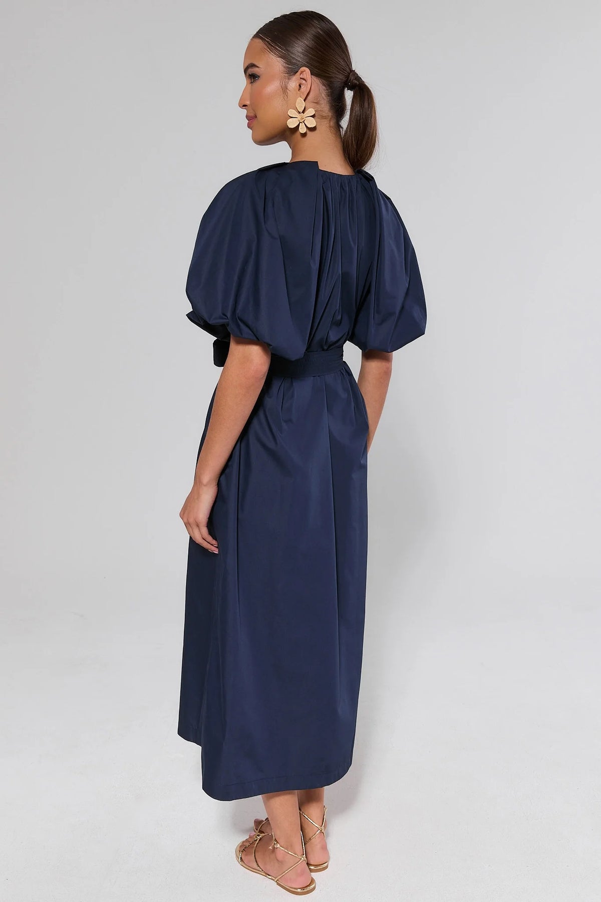 Back view of Meadow Navy Belted Midi Dress showing gathered puff sleeves and midi-length silhouette | Avara