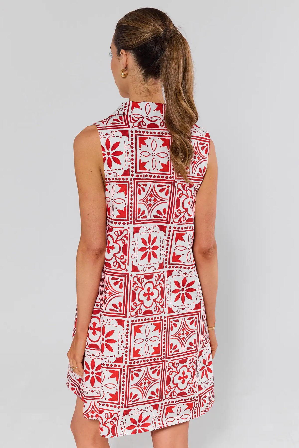 Woman standing wearing a red and white patterned dress on a gray background