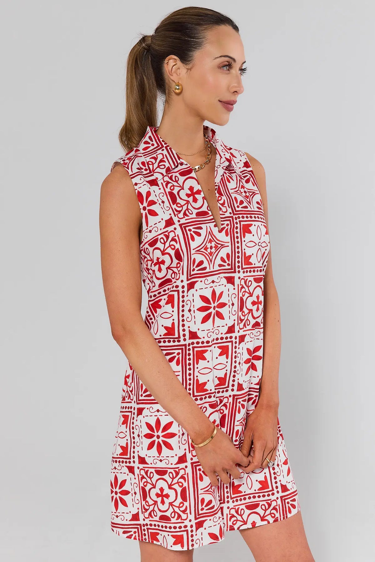 side shot Woman wearing a red and white patterned dress on a gray background
