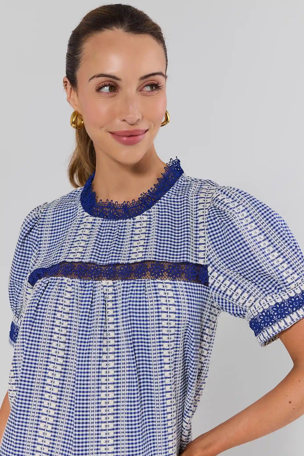 close up Woman wearing a blue and white checkered dress with decorative elements on a plain background