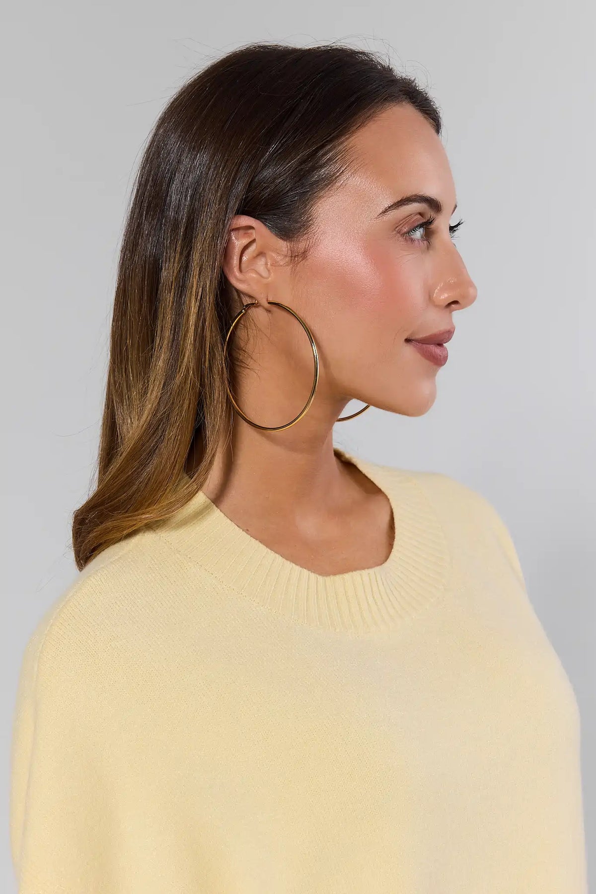 Woman wearing Lindsey Gold Large Hoop Earrings with yellow sweater - Side Profile | Avara