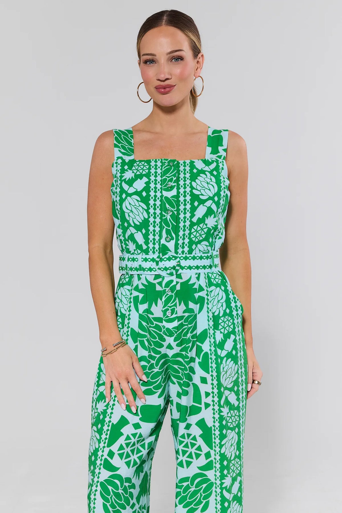 Woman wearing a green and white patterned jumpsuit on a plain background