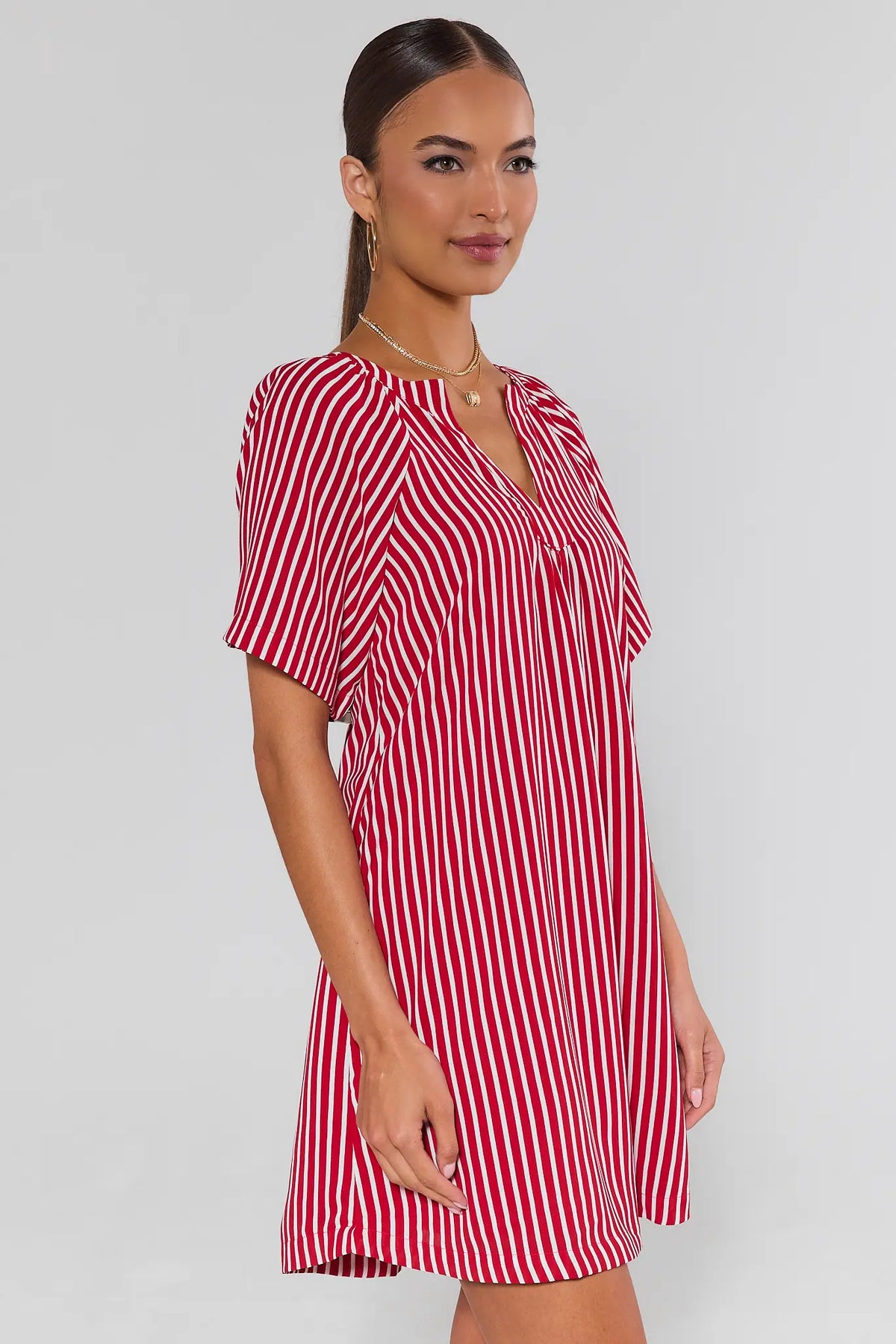 side shot Woman wearing a red and white striped dress against a plain background